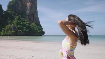 aantrekkelijke Aziatische schudt haar lange zwarte steil haar dat stroomt door de zeebries, vrouwelijk model fladdert haar, slow motion, een gezonde haarverzorging, zomervakantie op het strand, schoonheidsproduct video