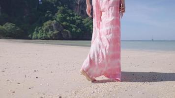 Shot from behind of female walking on the island beach, small calm waves, fresh air environment, Hot sunny weather, clear sky seascape, Freedom life escape from city, island summer vacation tourist video