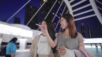 Happy cheerful asian close friend walking together on modern pedestrian bridge during evening time, teenage enjoying their youth and free time, female stylish outfits, women society, weekend activity