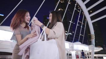 une jeune femme asiatique surprise heureuse et excitée de recevoir un cadeau d'anniversaire de sa meilleure amie, un cadeau pour une occasion spéciale, des femmes adultes joyeuses célébrant ensemble tout en marchant sur le pont de la ville video