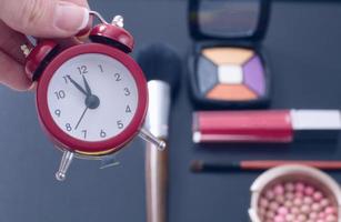 Concept cropped image with cosmetic and make up products. Quick make-up. Red retro clock. Selective focus photo