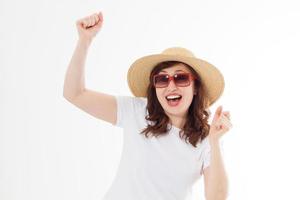 Happy surprised and excited woman in summer hat, sunglasses and template white t shirt isolated on white background. Holiday vacation with big sale. Fun summertime. Copy space, blank place on tshirt. photo