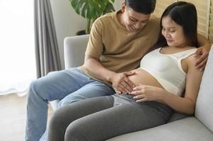 joven embarazada con marido abrazando y esperando un bebé en casa foto