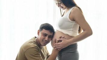 Young pregnant woman with husband embracing and expecting a baby at home photo