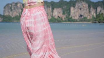 joven mujer bastante delgada usa ropa de playa tropical rosa caminando en la playa de arena. paseo relajante por la isla, paraíso secreto, plan de viaje, vlog de influencers, vacaciones de verano en asia, vista trasera