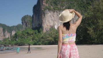 A fashionable pretty model strolling by a clean beach, showing a beautiful view of mountains and blue ocean, asia natural resources, spending time on vacation, healthy leisure activity on holiday video