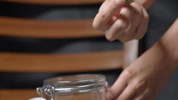 A gardener's hand showing an example of dried cannabis bud with putting in a transparent jar, smells fresh terpene, hands closing locking glass container lid, alternative herbal marijuana plant video