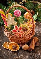 galletas de jengibre de navidad y piruletas en una canasta sobre fondo de madera vieja foto
