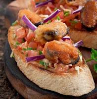 bruschetta con mejillones, queso y tomates foto