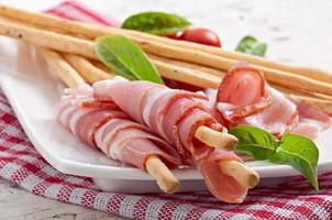 Grissini bread sticks with ham, tomato and basil photo