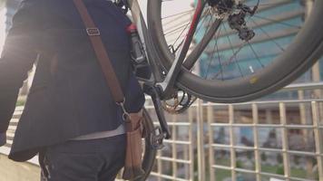 aktiv självsäker professionell ung affärsman som bär sin cykel på gatan eller bron, njuter av stadsutsikt på överfart, metallstaket i bakgrunden, promenad i staden, miljökoncept video