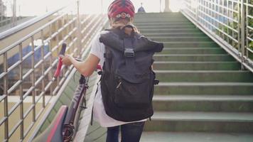 Young beautiful female jobber with helmet on head carrying bicycle walks the stairs in rush hour for people going to workplace , sustainable transport and living a healthy lifestyle, urban lifestyle video