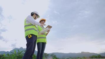 Male and female construction workers in safety working uniform standing and discuss works at outdoor construction site, technology innovation, real estate building industry, hard work engineers