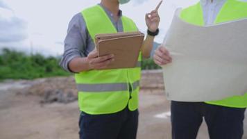 close up a male civil engineers on arguing on an outdoor construction site, building architect using blueprint with digital tablet on data collection, a real estate futuristic development and planning video