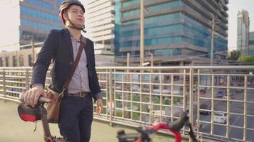 jovem empresário feliz e atraente empurrando sua bicicleta agradavelmente depois de terminar seu trabalho mais cedo, no caminho de volta para casa na cidade, use o viaduto para reduzir acidentes rodoviários, vida urbana diária da cidade video