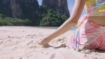 vue arrière d'une jeune femme excitée expérimentée en touchant un sable pour la première fois, une fille insouciante jouant avec un grain de sable, le faisant couler à travers la brise de l'océan, le bonheur des vacances d'été sur l'île video