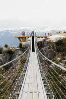 Suspension bridge and snowcapped mountains photo