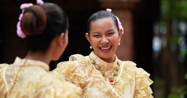 Handaufnahme, selektiver Fokus, junge schöne Frauen mit traditioneller thailändischer Tracht genießen es, Wasser im Tempel auf dem Songkran-Festival zu spritzen. thailändisches neujahr, thailändische kultur mit wasserfest video