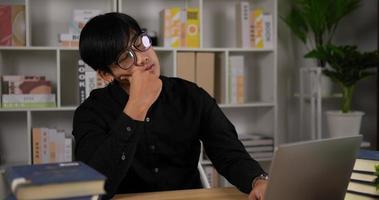 fatigué jeune homme d'affaires asiatique professionnel enlever les lunettes. un homme massant les yeux secs et irrités qui démangent ressentent une fatigue oculaire des maux de tête une fatigue après le travail sur ordinateur de bureau assis au bureau. video