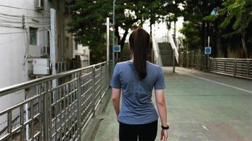Back view young woman athlete walking on the street after a run.