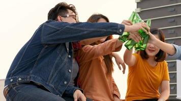 Group of young people clinking bottles of beer party on rooftop. video