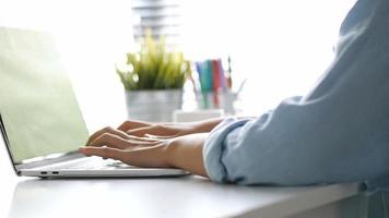 cierre la mano escribiendo en un ordenador portátil con teclado en la oficina. una mujer joven que solo usa una computadora de escritorio. video