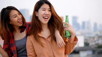 Woman lesbian couple clinking bottles of beer party on rooftop. video