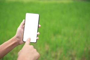 mano de primer plano usando un teléfono inteligente con pantalla en blanco al aire libre. foto