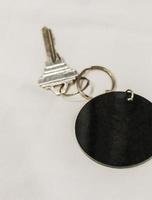 Hotel room key with round black blank pendant white background. photo