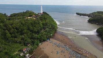 veduta aerea della spiaggia tropicale in indonesia con faro e barca tradizionale. video