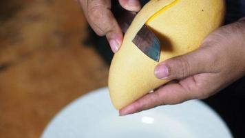 Using a knife to peel ripe mangos