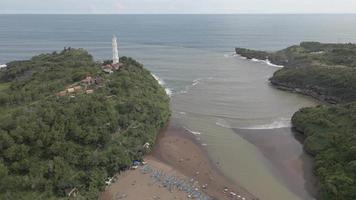 Aerial view of Tropical Beach in Indonesia with lighthouse and traditional boat.