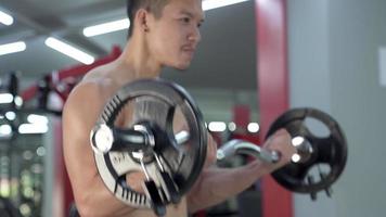 Hombre deportivo entrenando con una barra pesada en el gimnasio. video