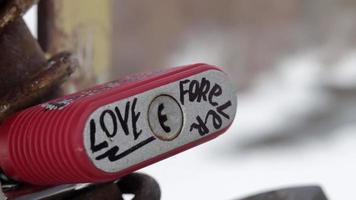 die Inschrift in englischer Liebe für immer auf einem roten Vorhängeschloss. Die verschlossenen Liebesschlösser, die an der Brücke befestigt sind, symbolisieren unzerbrechliche Liebe. Hand geschossen. video