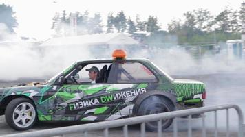 coche a la deriva, conductor profesional. coche de carreras a la deriva con humo espeso de neumáticos quemados. agotamiento de autos de carrera. en coche texto en física rusa del movimiento. ucrania, kiev - 22 de julio de 2021. video