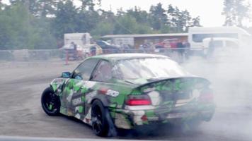 driftendes Auto, Berufskraftfahrer. Renndriftwagen mit dickem Rauch aus brennenden Reifen. Burnout im Rennwagen. mit dem auto text in der russischen bewegungsphysik. ukraine, kiew - 22. juli 2021. video