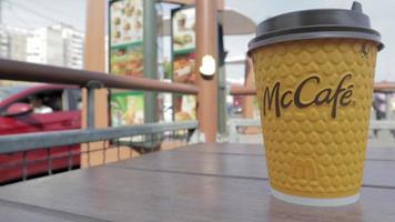 Yellow cardboard coffee cup from McDonald's. Mc Cafe paper glass drink. One coffee cup on the table with hot tea or coffee. Menu in a fast food restaurant. Ukraine, Kiev - September 12, 2021. video