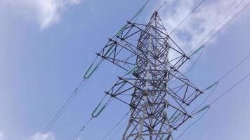 Time-lapse scene of electric high-voltage tower against a blue sky with fast-moving white clouds. video