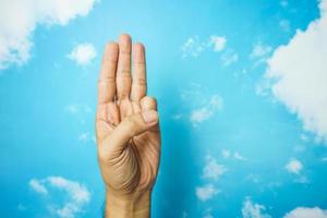 símbolo de la mano aislado del fondo del cielo. concepto de lenguaje de señas foto