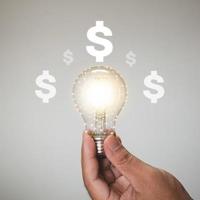 Hand holding a light bulb with increasing for business growth and profit increase concept. photo