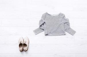 Different female clothes on white wooden background. Top view. Mock up. Copy space. Summer shirt. Shoes photo