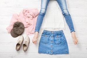 Casual summer outfit with different accessories and female legs in jeans on white wooden floor. Top view and copy space. photo