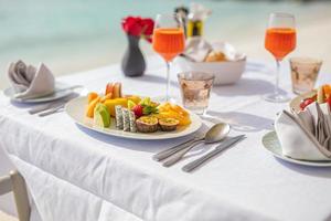 Fresh breakfast in a beautiful location with sea views. Luxury summer vacation or honeymoon destination. Table with gourmet delicious food near the sea with horizon. Beautiful summer breakfast setting photo
