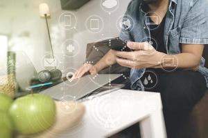 designer man hand using laptop compter and mobile payments online shopping,omni channel,sitting on sofa in living room,green apples in wooden tray,graphic interfce icons virtual screen photo