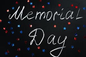 Handwritten inscription Memorial Day on a black chalkboard and American blue and red stars on background. Holiday concept. photo