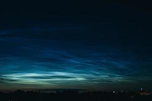 Noctilucent mesospheric clouds in night sky. Rare atmospheric phenomenon over city. photo