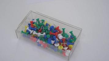 Colored push pins in plastic box on white table video