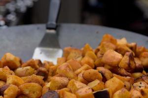 Chunks of fried potatoes in a large skillet during the street food festival. photo