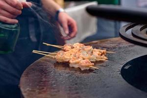 Cooking shrimp, prawn skewers on grill at street food festival - close up