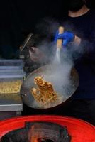 un chef prepara comida china en un festival de comida callejera.